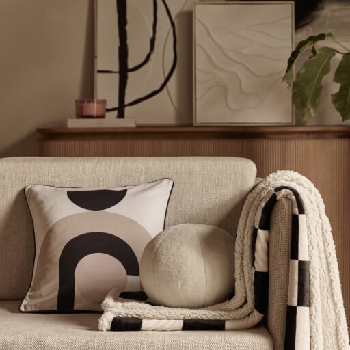 Cream sofa with abstract patterned cushion and throw.