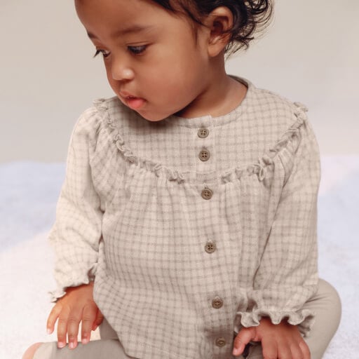 Baby wearing neutral check pattern dress.
