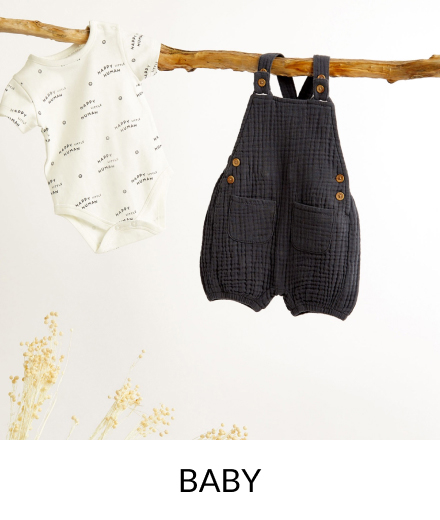 A white bodysuit and navy dungarees hanging from a branch.