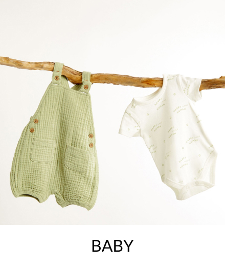 A green and white baby outfit hanging up.